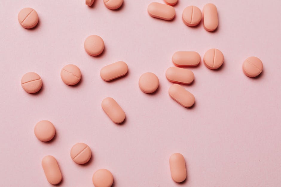 Flat lay photo of pink pills on a pastel pink background, ideal for pharmaceutical themes.