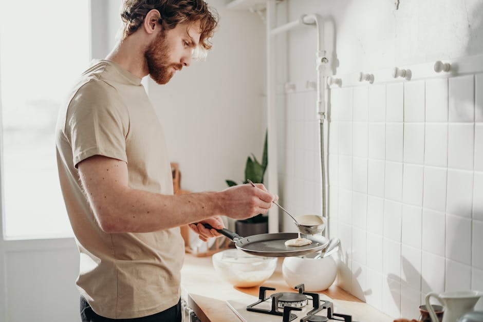 Man making pancakes in a sunlit kitchen, capturing the casual morning routine.