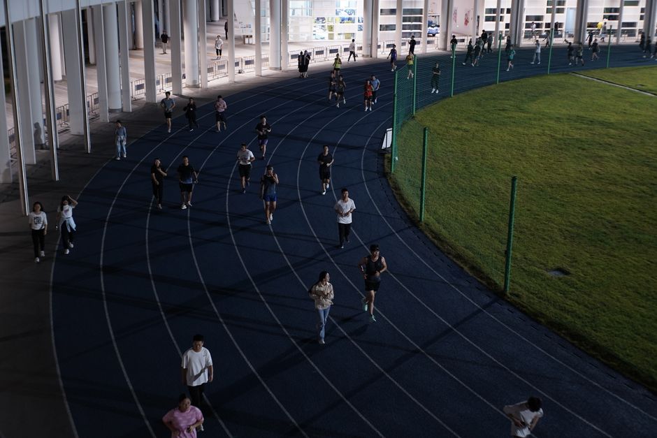 A group of people jogging on an outdoor track in the evening, showcasing urban fitness culture.