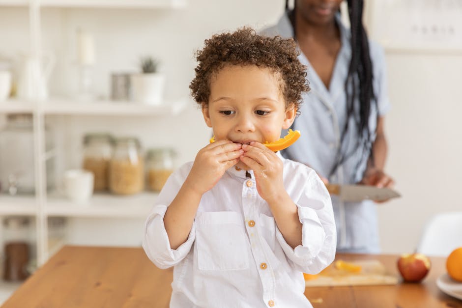 A young child enjoys a slice of fruit in a bright, modern kitchen setting.